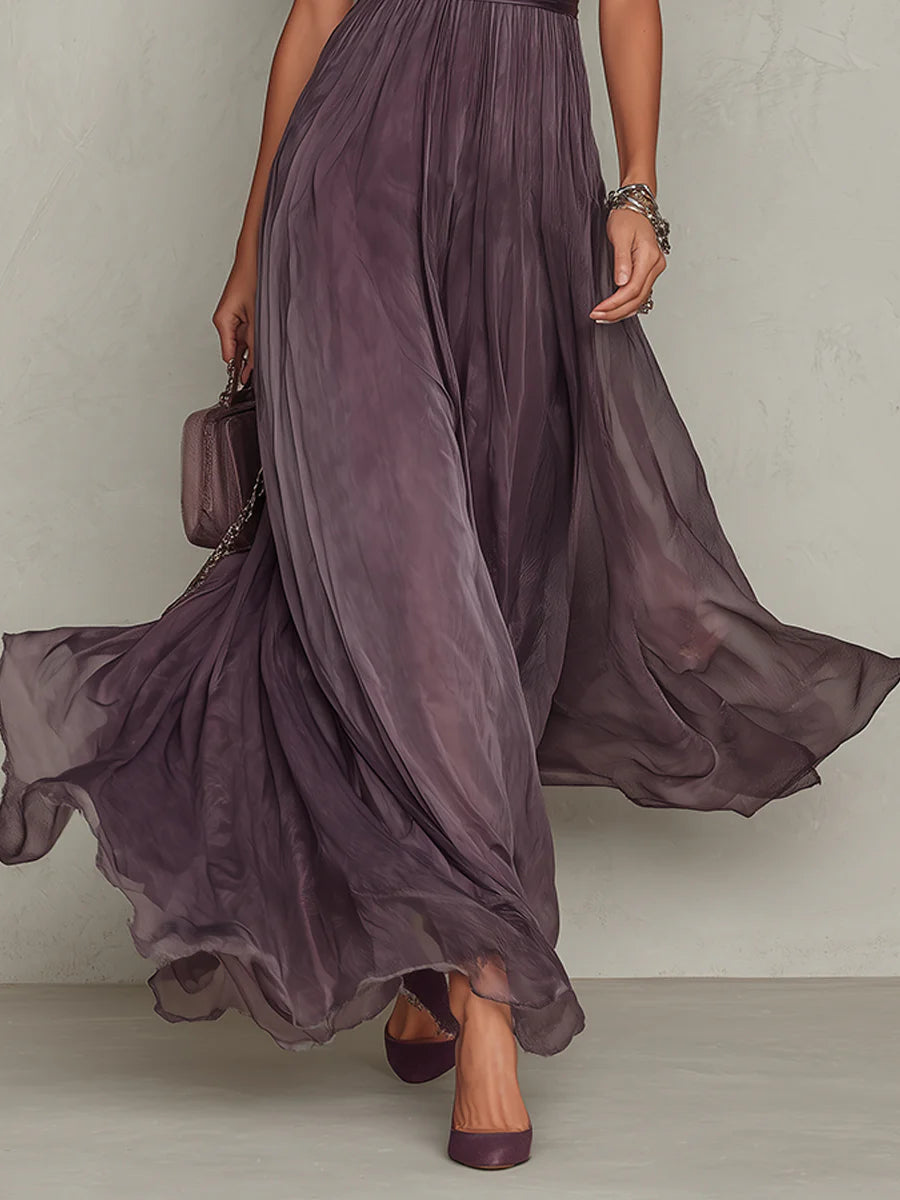 Détail de la jupe longue et fluide de la robe prune en voile, avec reflets dégradés, portée avec escarpins et petit sac. 5