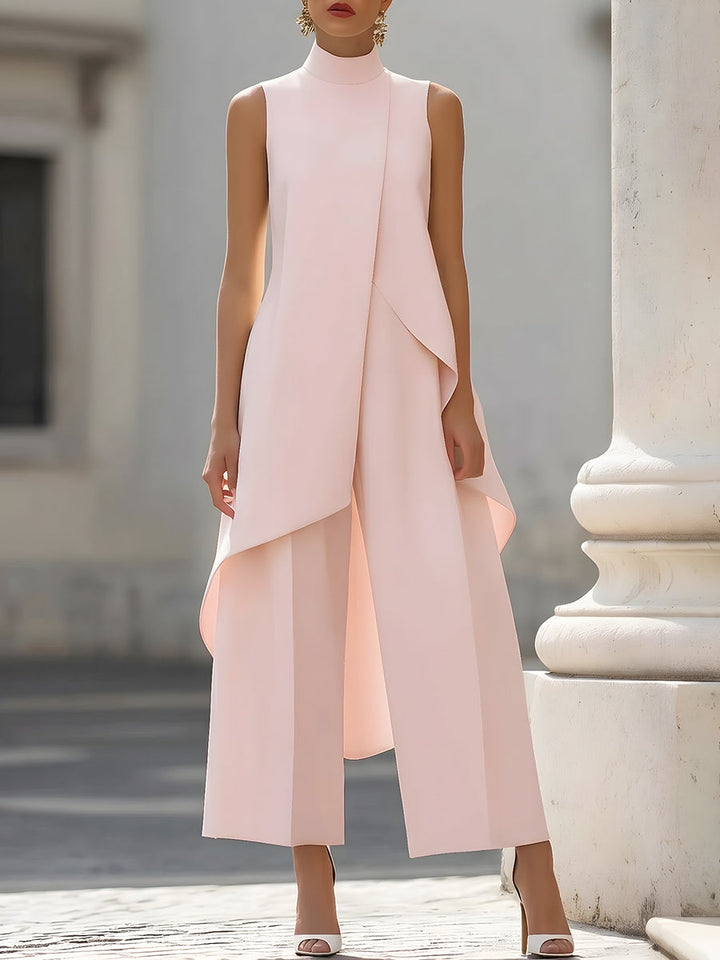 Version rose poudré portée de face devant une colonne, avec le pan asymétrique du haut posé sur le pantalon large. 7