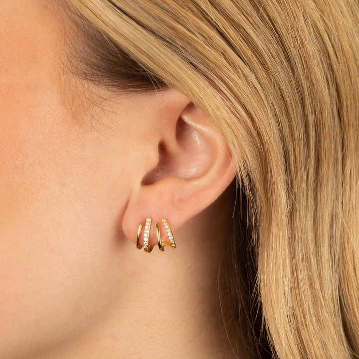 Oreille d'une femme blonde portant la boucle dorée à quatre griffes, dont deux ornées de petits strass 4
