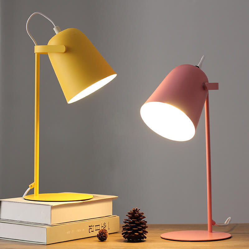 Deux lampes allumées côte à côte, l'une jaune sur une pile de livres, l'autre rose sur la table, avec une pomme de pin. 5