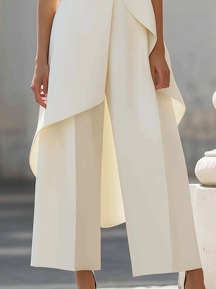 Gros plan sur le bas de l'ensemble : pantalon large à plis et pan asymétrique du haut qui se superpose en drapé. 12