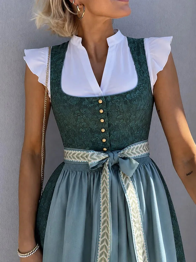 Gros plan sur le buste de la robe verte à motif tonal, boutons dorés, encolure carrée et ruban noué à chevrons. 5