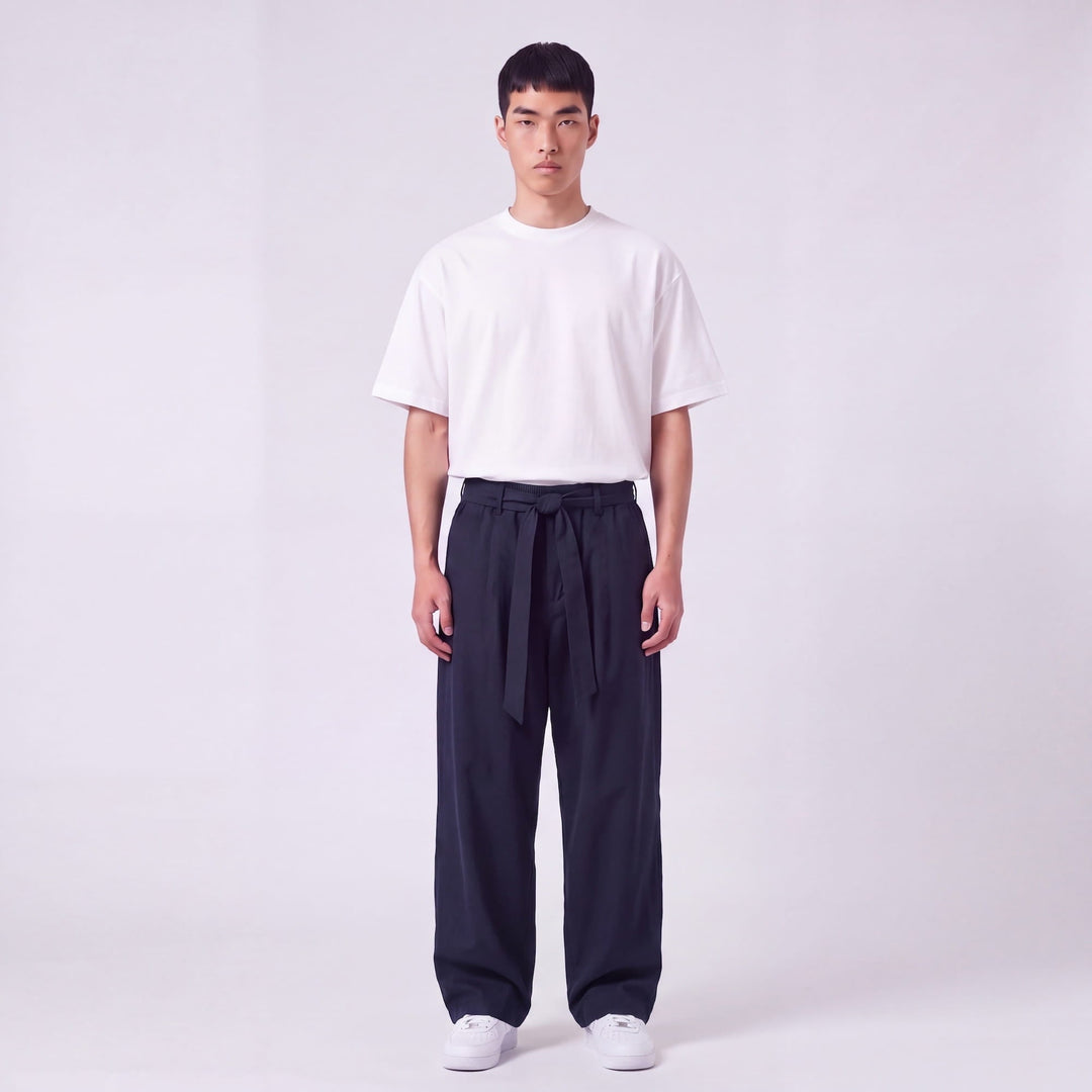 Mannequin de face en pied portant le pantalon large bleu marine, ceinture nouée à la taille, avec t-shirt blanc oversize. 2