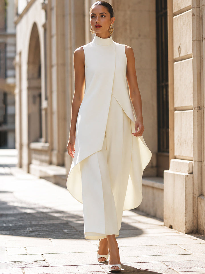 Mannequin en marche dans une rue ensoleillée bordée de façades en pierre, ensemble blanc cassé au pan asymétrique arrondi. 9