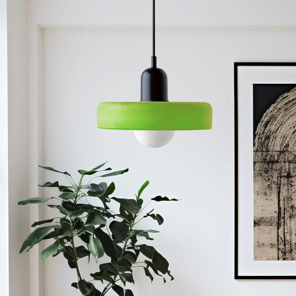 Suspension à abat-jour vert pomme et capuchon noir dans un salon lumineux, près d'une plante verte et d'un cadre. 3