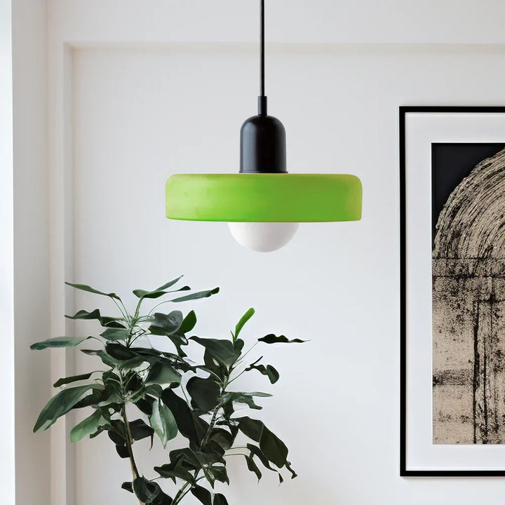 Suspension à abat-jour vert pomme et capuchon noir dans un salon lumineux, près d'une plante verte et d'un cadre. 3