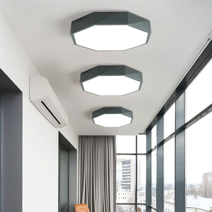 Trois plafonniers octogonaux gris de tailles différentes alignés au plafond d'un couloir vitré 2