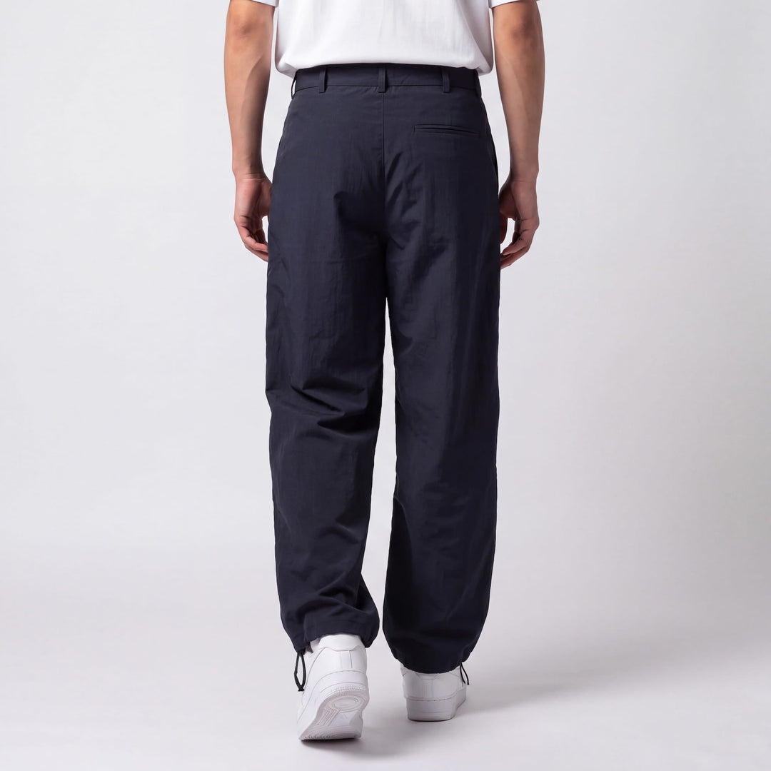 Vue de dos du pantalon bleu marine montrant la poche passepoilée arrière et les cordons de serrage aux chevilles. 6