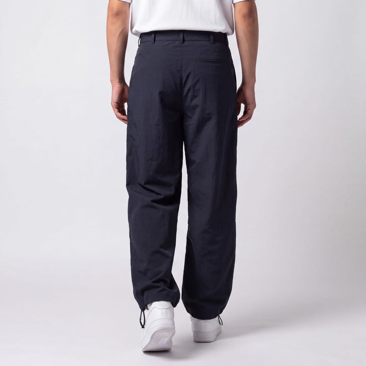 Vue de dos du pantalon bleu marine montrant la poche passepoilée arrière et les cordons de serrage aux chevilles. 6