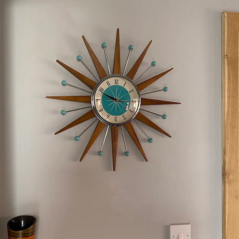 Horloge étoile accrochée dans une pièce, au-dessus d'une prise murale, près d'un montant de porte en bois clair. 5