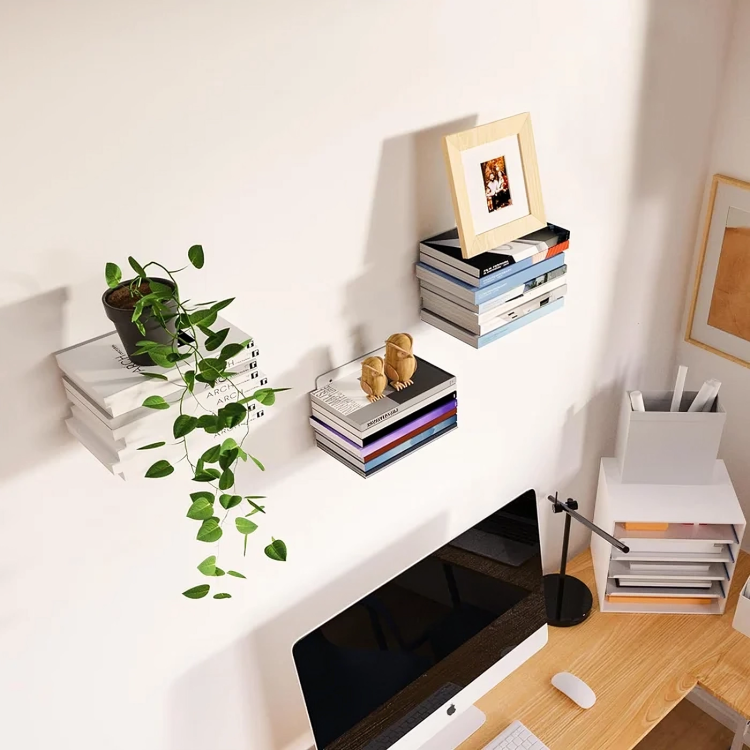 Vue plongeante sur trois piles de livres suspendues au mur au-dessus d'un bureau, avec plante retombante, cadre photo et figurines en bois. 4