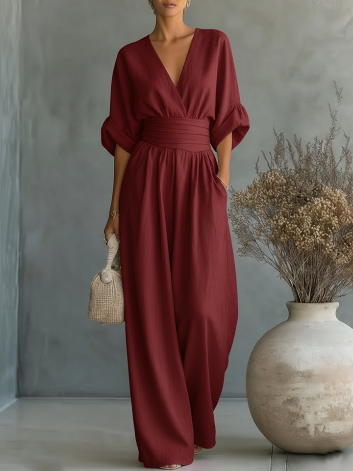 Combinaison rouge bordeaux portée par une femme, main dans la poche, avec grand vase et fleurs séchées 9