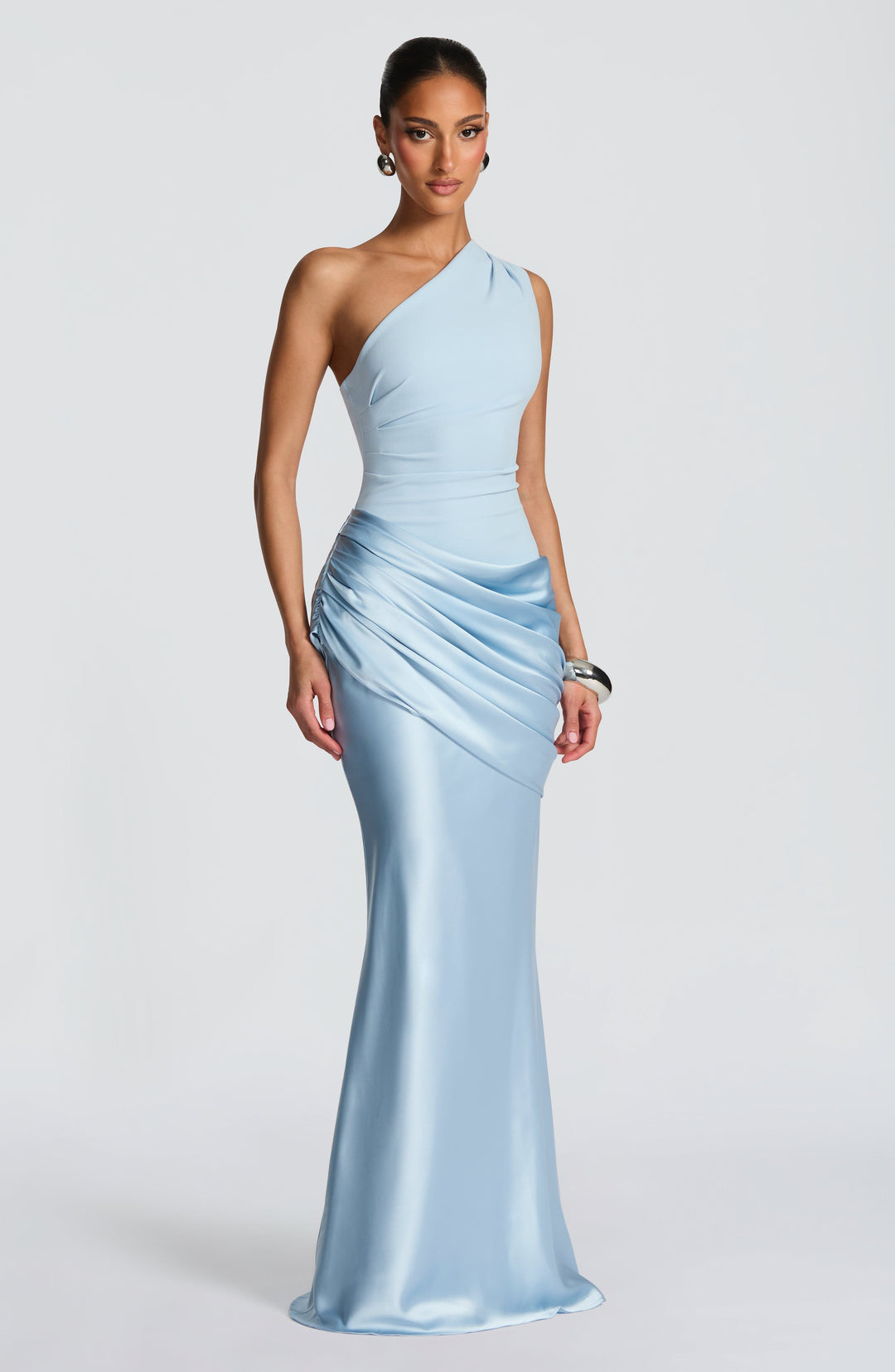 Robe longue bleu ciel portée en trois quarts, épaule dénudée, jupe en satin fluide évasée vers le bas. 3
