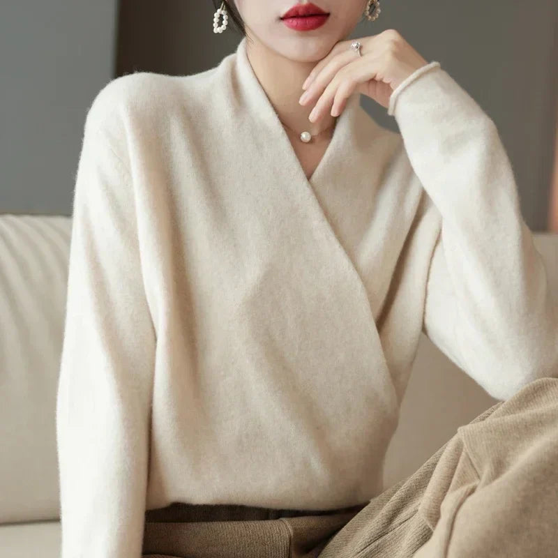 Pull croisé écru porté avec une main sous le menton, assise sur un canapé beige 10