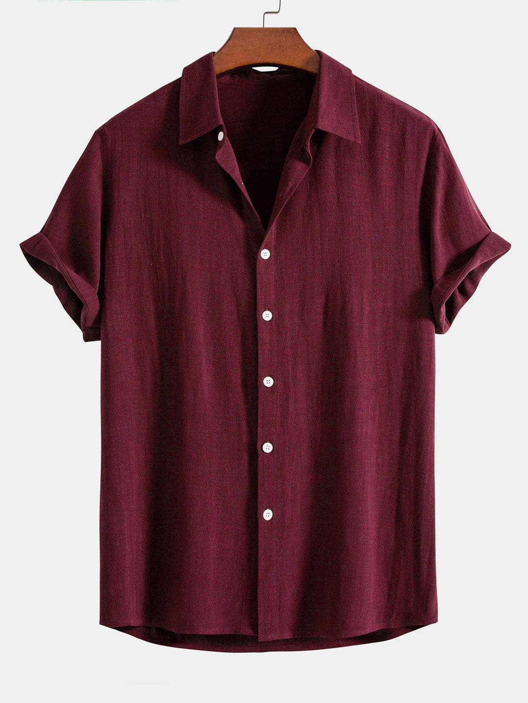 Chemise à manches courtes retroussées, coloris bordeaux, sur cintre en bois, vue de face avec boutons blancs. 7