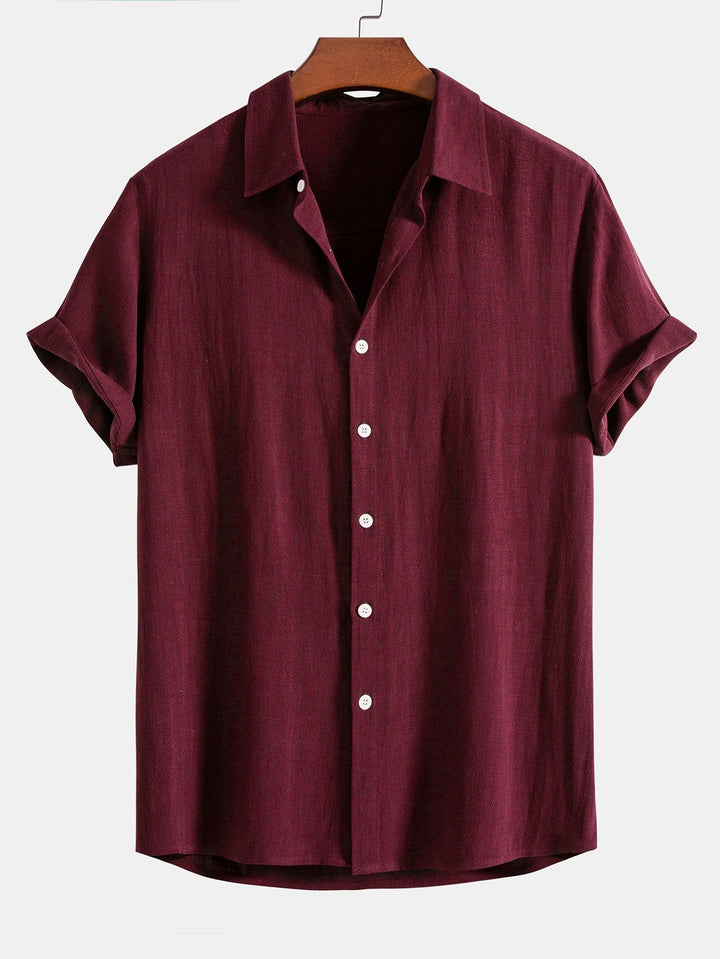 Chemise à manches courtes retroussées, coloris bordeaux, sur cintre en bois, vue de face avec boutons blancs. 7