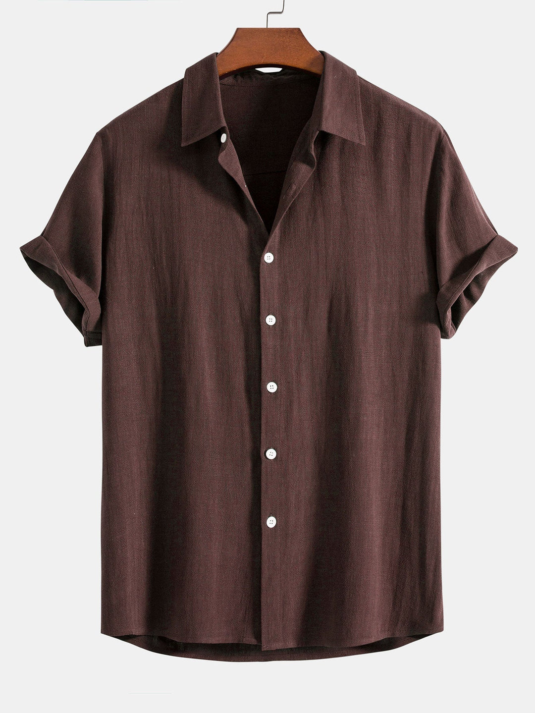 Chemise à manches courtes retroussées, coloris marron foncé, sur cintre en bois, vue de face avec boutons blancs. 8