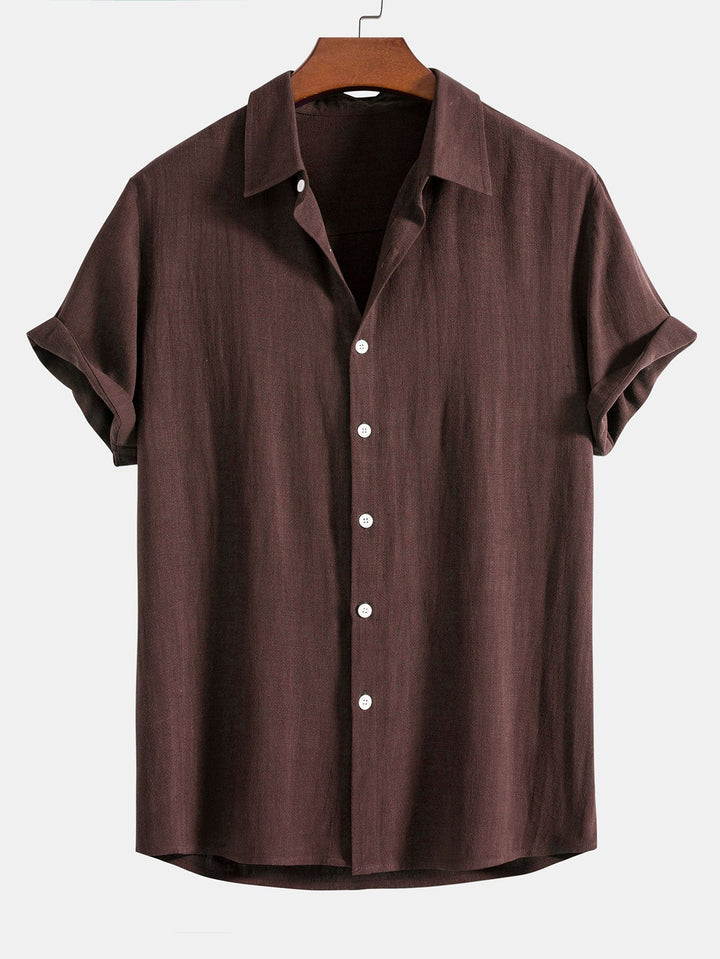 Chemise à manches courtes retroussées, coloris marron foncé, sur cintre en bois, vue de face avec boutons blancs. 8