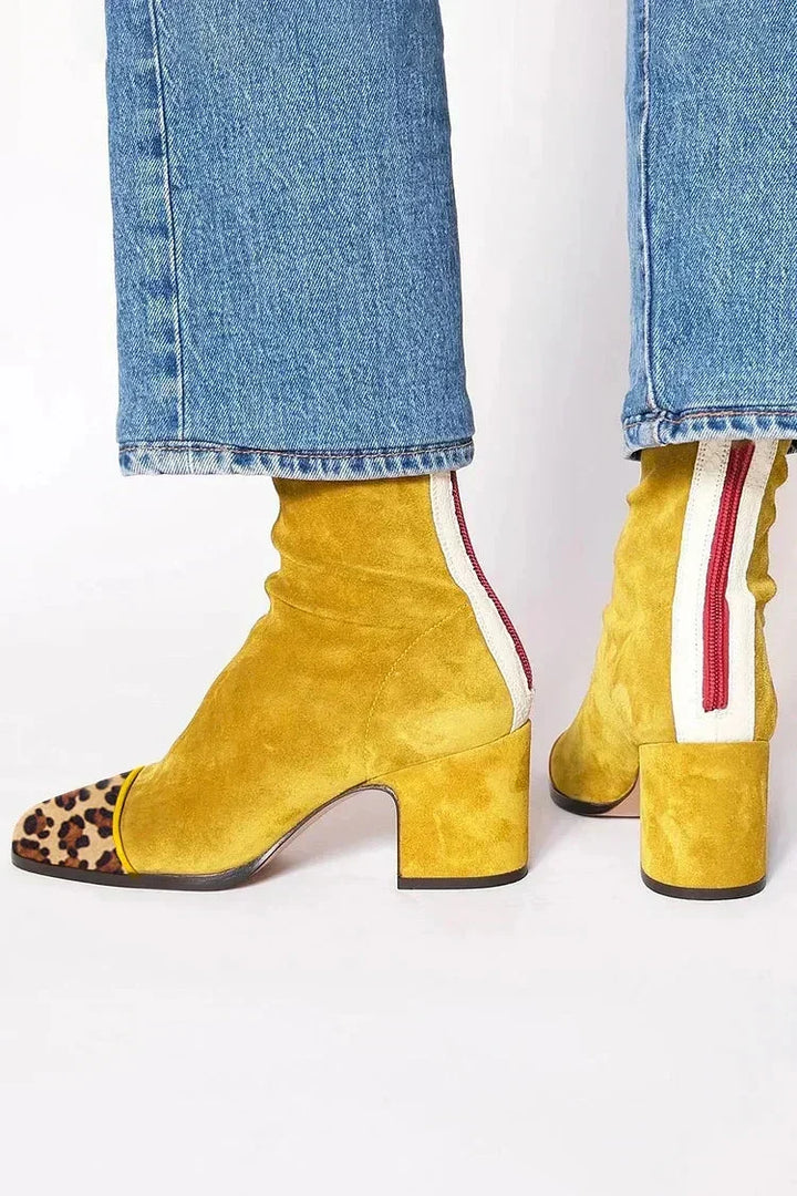 Bottines en daim jaune moutarde à bout léopard, zip rouge et bande blanche à l'arrière, portées avec un jean. 5