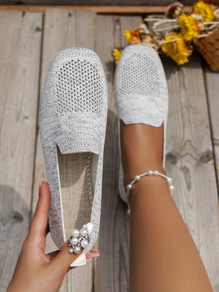 Vue de dessus de la paire gris clair en mesh ajouré, un soulier tenu à la main avec une semelle intérieure texturée beige. 15