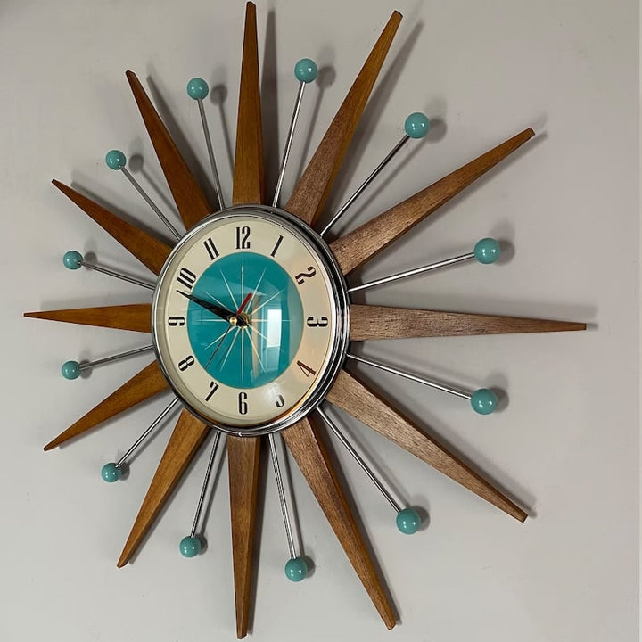 Horloge en étoile vue légèrement de biais sur un mur gris, montrant l'ombre portée des rayons en bois et des tiges chromées. 3