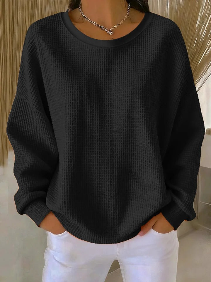 Pull gaufré noir à col rond et manches longues, porté mains dans les poches avec un pantalon blanc. 7