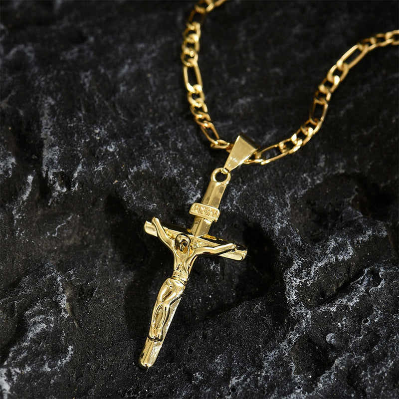 Crucifix doré sur chaîne Figaro posé sur une roche sombre texturée 9
