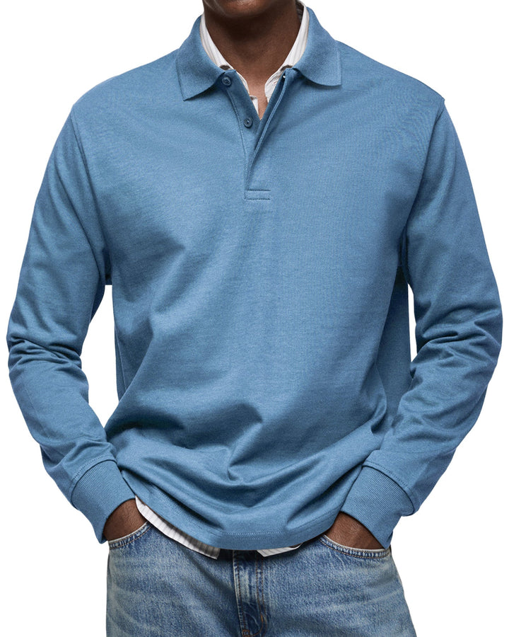 Polo à manches longues bleu ciel porté par un homme, mains dans les poches, col et poignets côtelés visibles, sur chemise rayée. 2