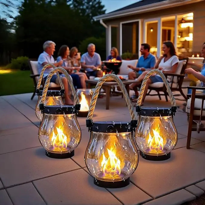 Trois lanternes à flamme sur une terrasse, avec des gens installés autour d'une table en soirée 5
