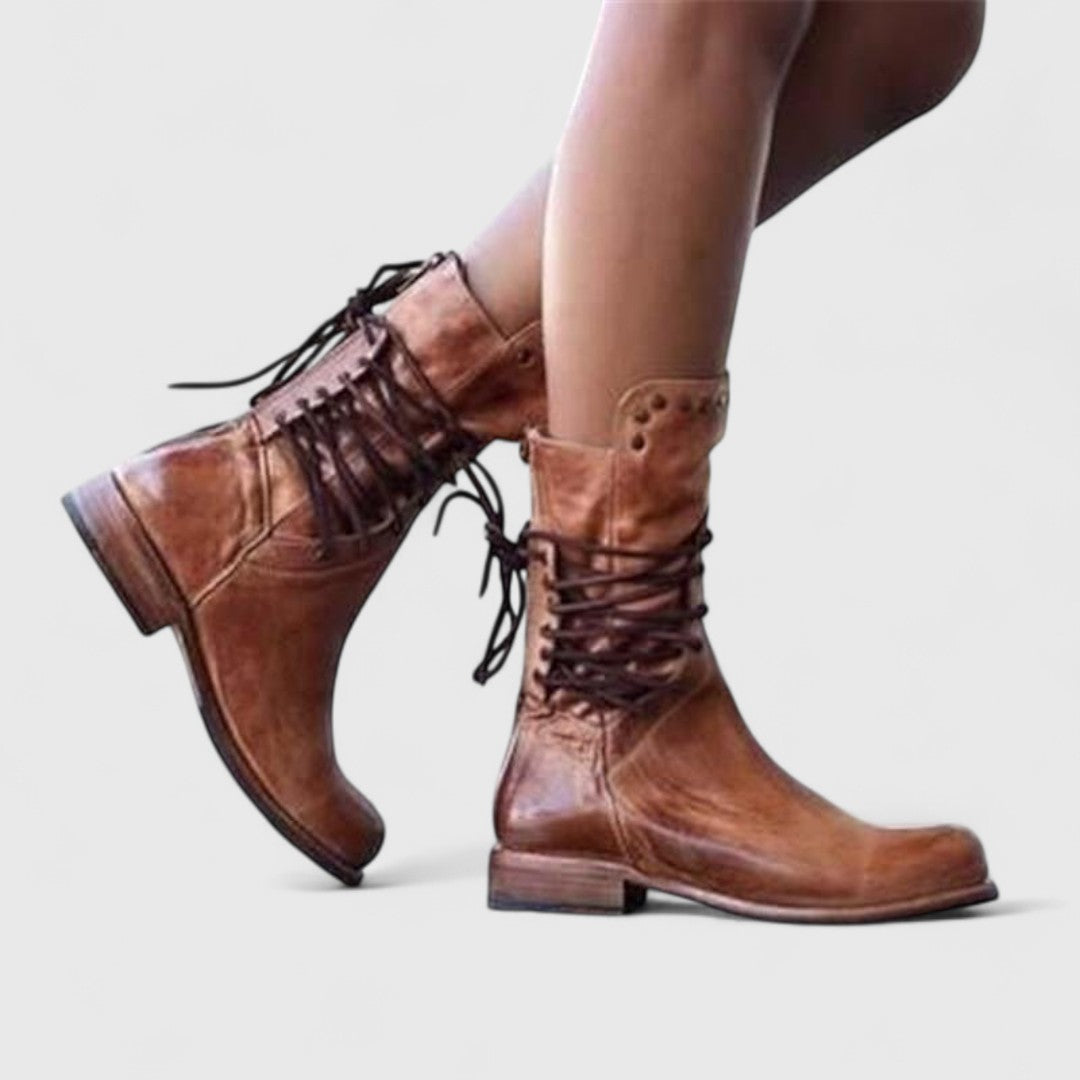 Bottes brunes aspect vieilli portées en marche, vues de profil, lacets croisés à l'arrière de la tige. 8