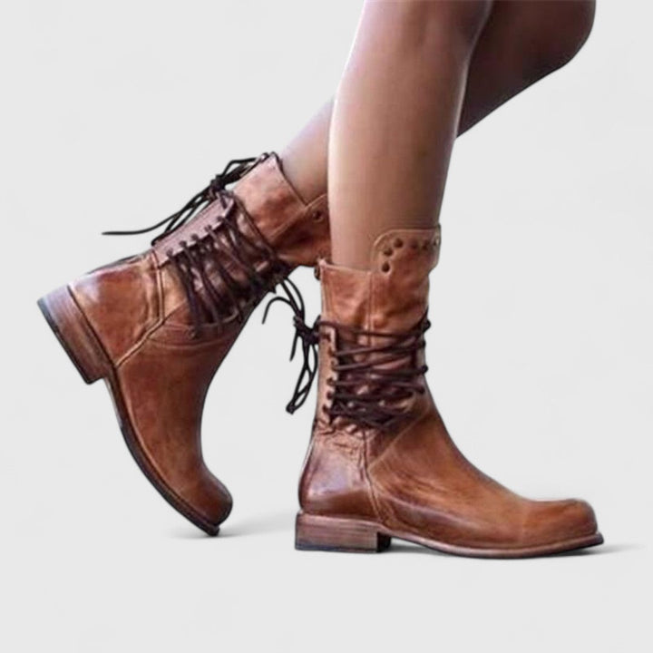 Bottes brunes aspect vieilli portées en marche, vues de profil, lacets croisés à l'arrière de la tige. 8