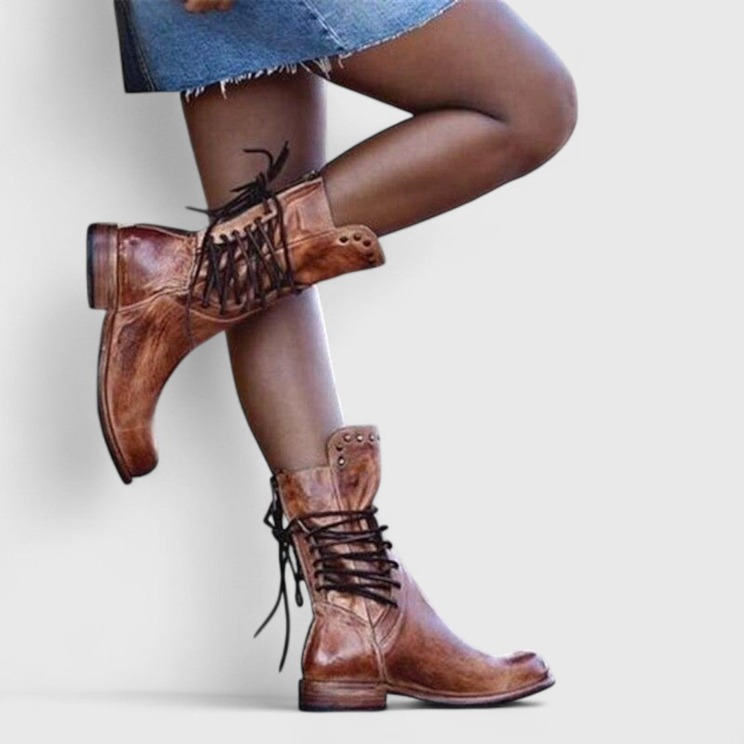 Mannequin en jupe en jean, jambe repliée, portant des bottes brunes aspect vieilli avec lacets arrière et rivets. 9