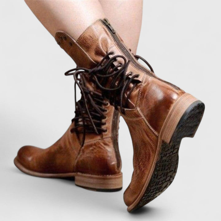Bottes brunes vues de dos en pleine marche, fermeture éclair à l'arrière, lacets croisés et semelle crantée visible. 10