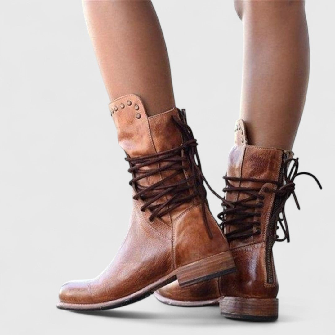 Bottes brunes portées en marche, vues de dos: rivets au col, lacets croisés sur la tige et zip arrière. 11