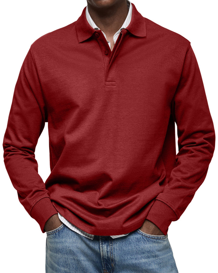 Polo à manches longues rouge bordeaux porté par un homme, mains dans les poches, chemise rayée apparente et jean bleu clair. 11