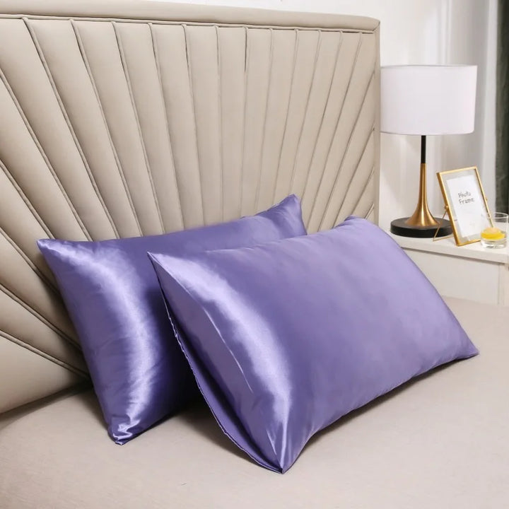 Deux taies satinées violet lavande sur un lit, devant une tête de lit beige et une lampe 4