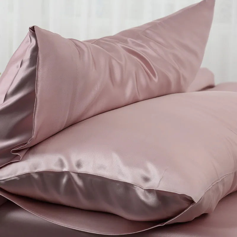 Gros plan sur deux taies satinées rose poudré empilées, avec l'ourlet et la doublure brillante bien visibles 1