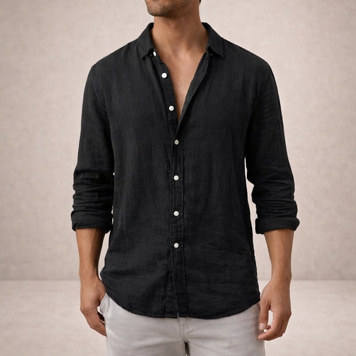 Chemise en lin noire portée de face avec un pantalon clair, boutons blancs, col ouvert et manches retroussées. 5