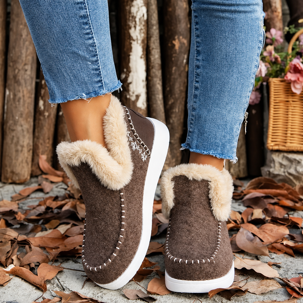 Paire marron portée vue de trois quarts arrière, avec col duveteux beige, broderie de flocons et semelle blanche. 2