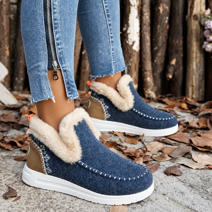 Paire bleu marine portée vue de profil, avec talon fauve, broderie de flocons, languette orange et col en peluche. 10