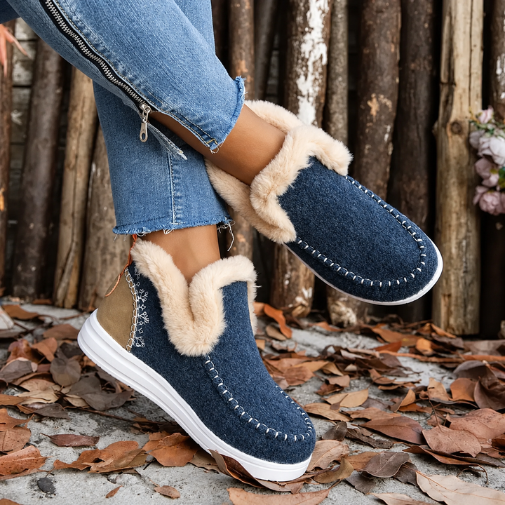 Paire bleu marine portée, pieds croisés, avec talon contrasté fauve, broderie sur le côté et col en fourrure beige. 4