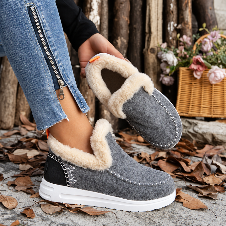 Paire grise avec contrefort noir, un pied porté et l'autre tenu à la main pour montrer la doublure en peluche. 5