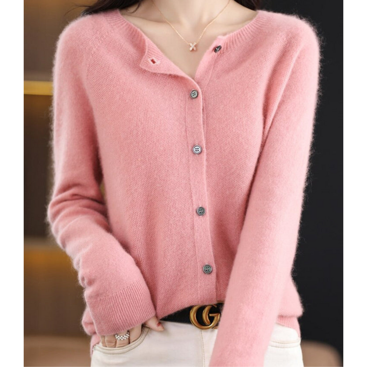 Cardigan rose clair en maille douce et duveteuse, boutons nacrés gris, porté avec un pantalon blanc et un collier. 2