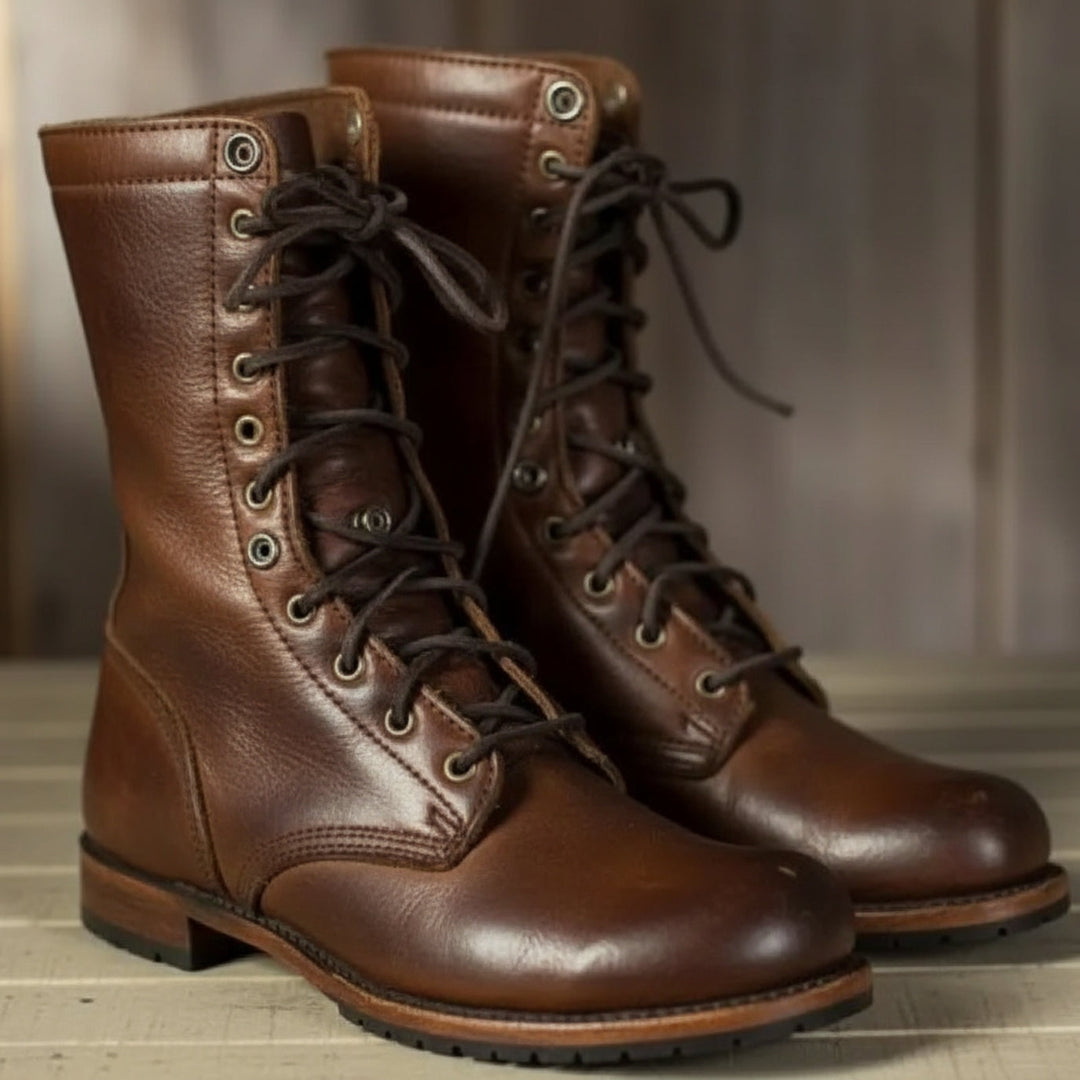 Paire de bottes montantes en cuir brun lisse, vue de trois quarts avec lacets sombres et œillets métalliques, posée sur du bois. 1