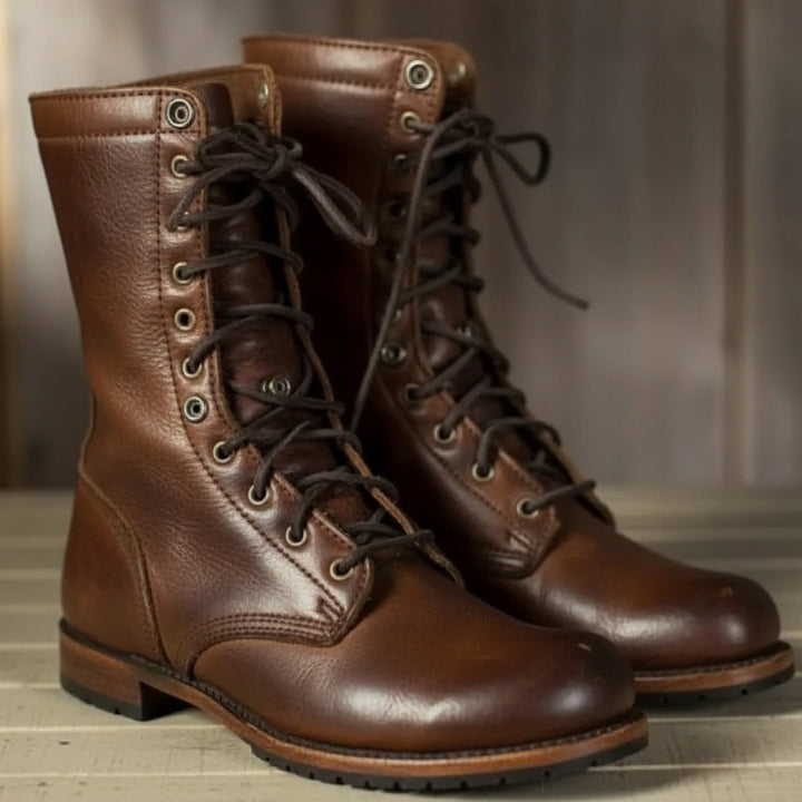 Paire de bottes montantes en cuir brun lisse, vue de trois quarts avec lacets sombres et œillets métalliques, posée sur du bois. 1