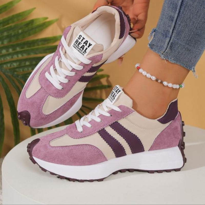 Baskets roses et beiges à bandes violettes, une chaussure levée, près d'une feuille de palmier 11