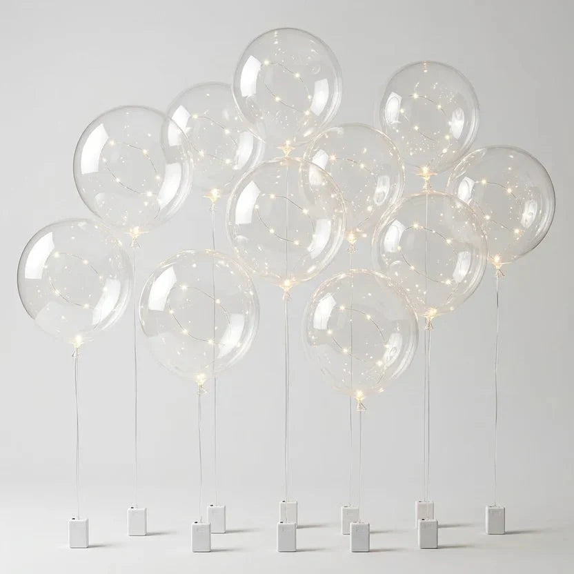 Dix ballons transparents à guirlande LED sur tiges, avec leurs boîtiers à piles blancs, sur fond neutre 8