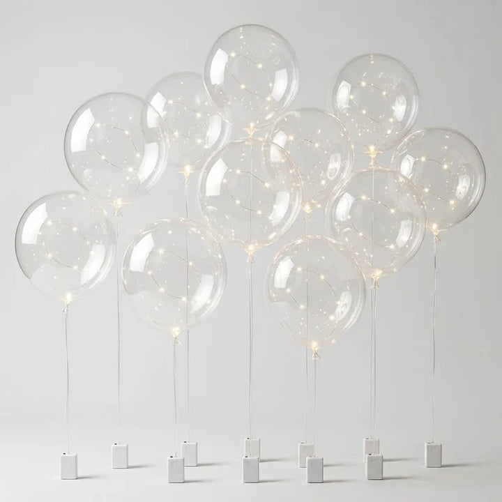 Dix ballons transparents à guirlande LED sur tiges, avec leurs boîtiers à piles blancs, sur fond neutre 8