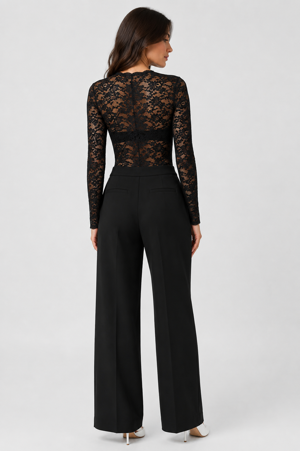 Vue de dos du body en dentelle noire transparente, manches longues, porté avec un pantalon noir large et des escarpins blancs. 4