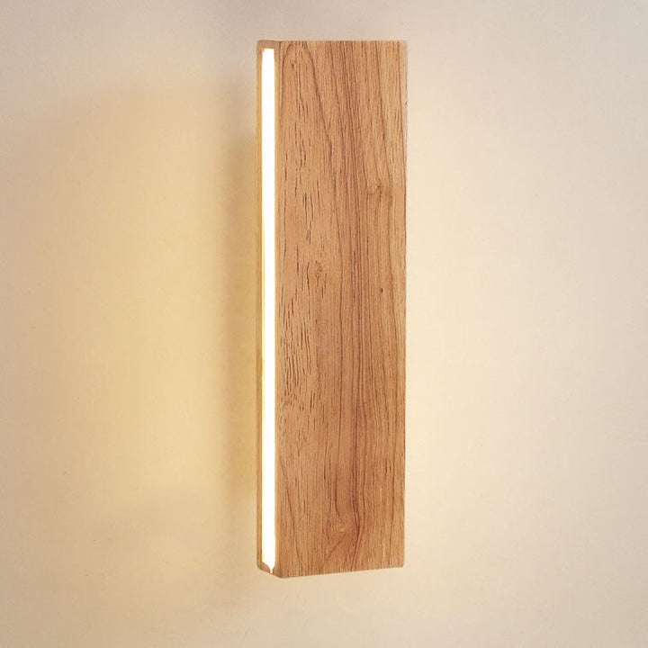 Gros plan sur le bois clair veiné de l'applique verticale, allumée, avec la bande lumineuse sur le bord gauche. 14